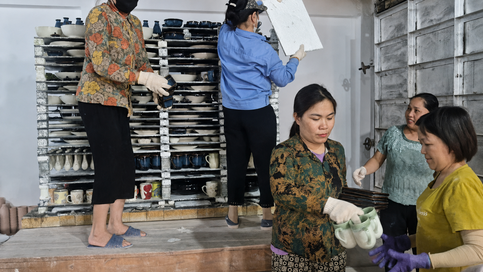 Worker glazing handmade ceramics at a Bat Trang glaze workshop